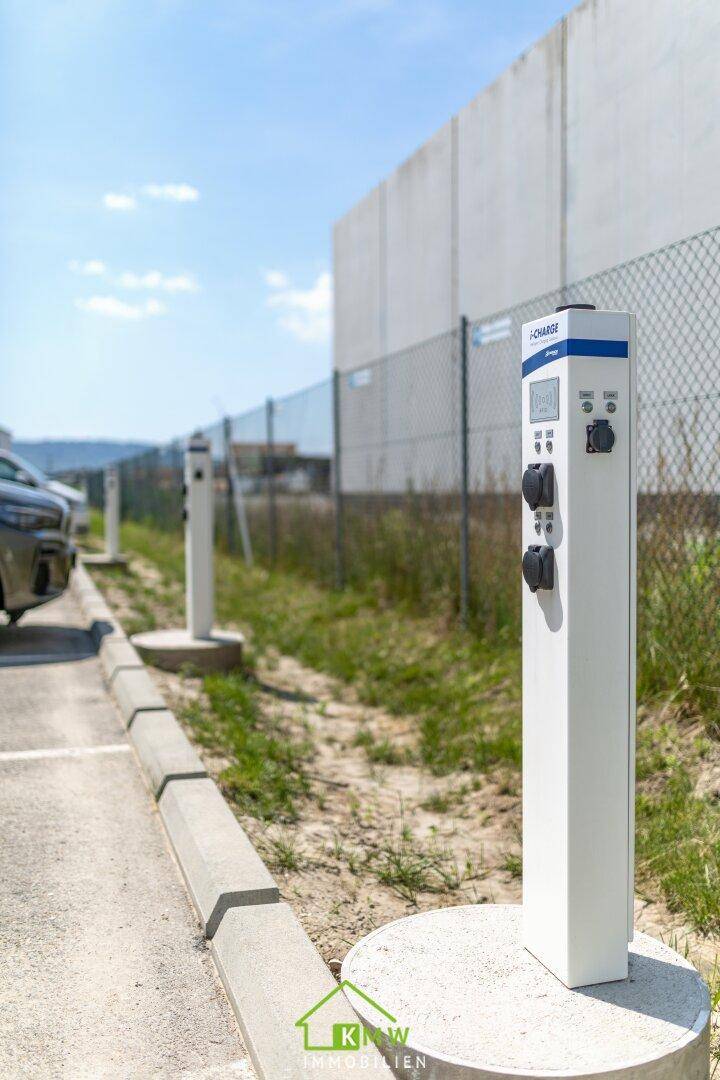 Außenbereich mit mehreren Ladestationen für Elektrofahrzeuge auf einem Parkplatz.