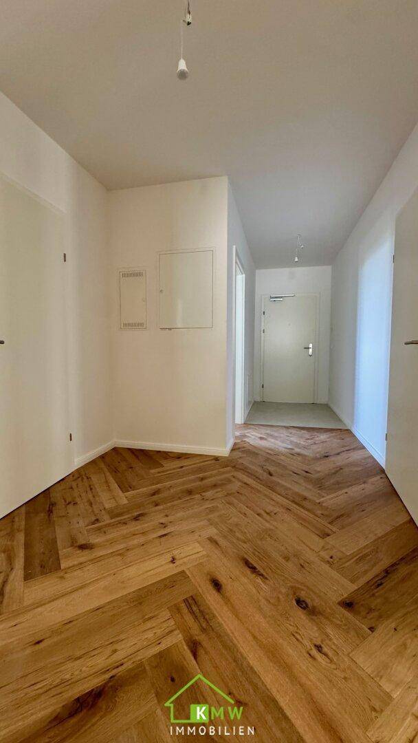 Eingangsbereich mit Fischgrätparkett und weißen Wänden, der einen hellen Empfang bietet.