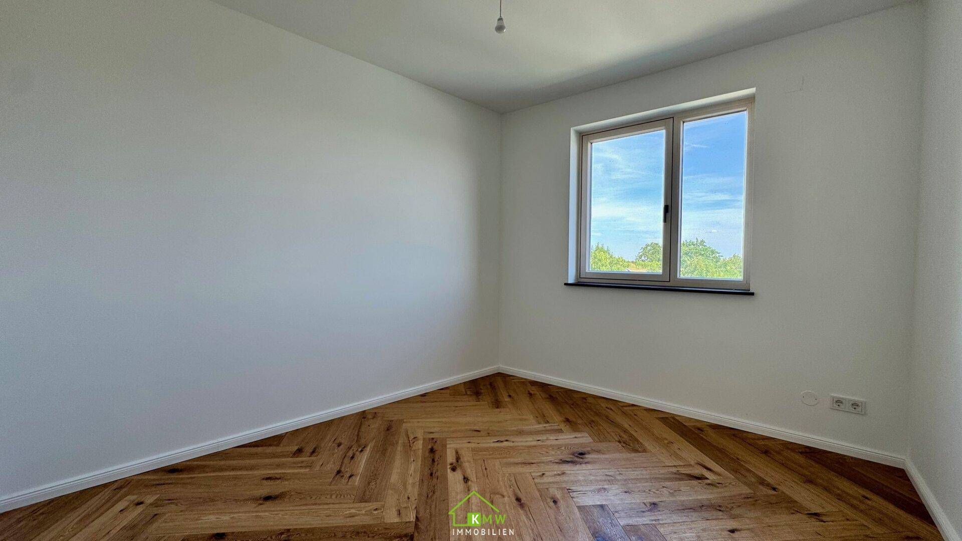 Geräumiges Zimmer mit Fischgrätparkett und einem großen Fenster für optimale Belichtung.