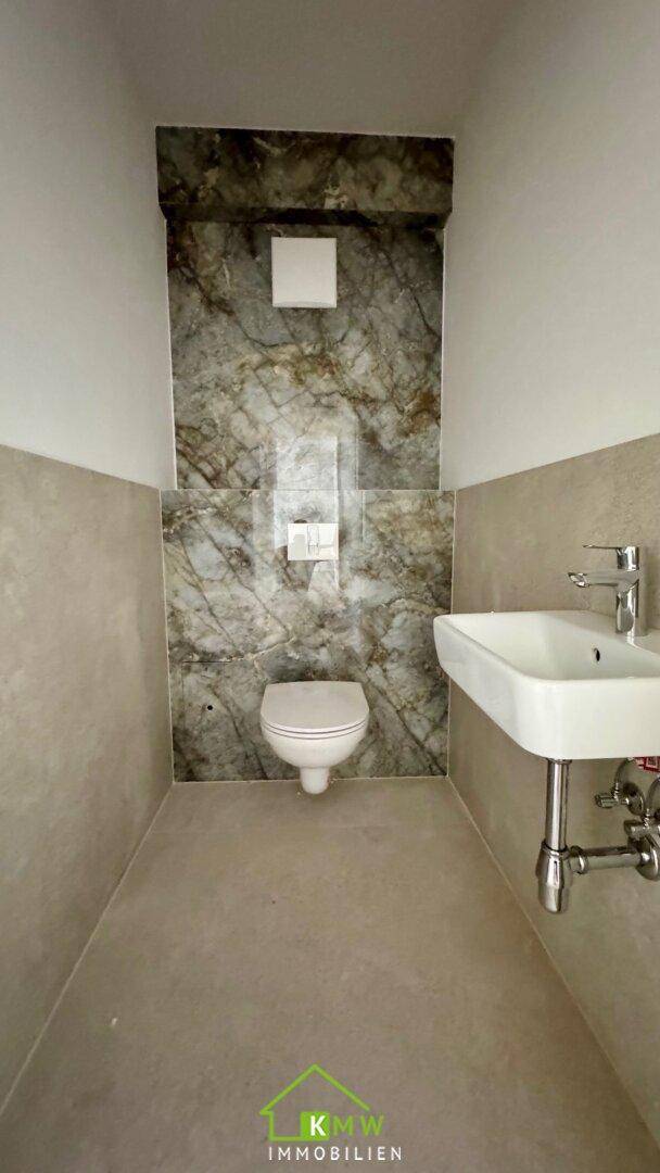 Separates WC mit wandhängender Toilette und modernem Einzelwaschbecken.