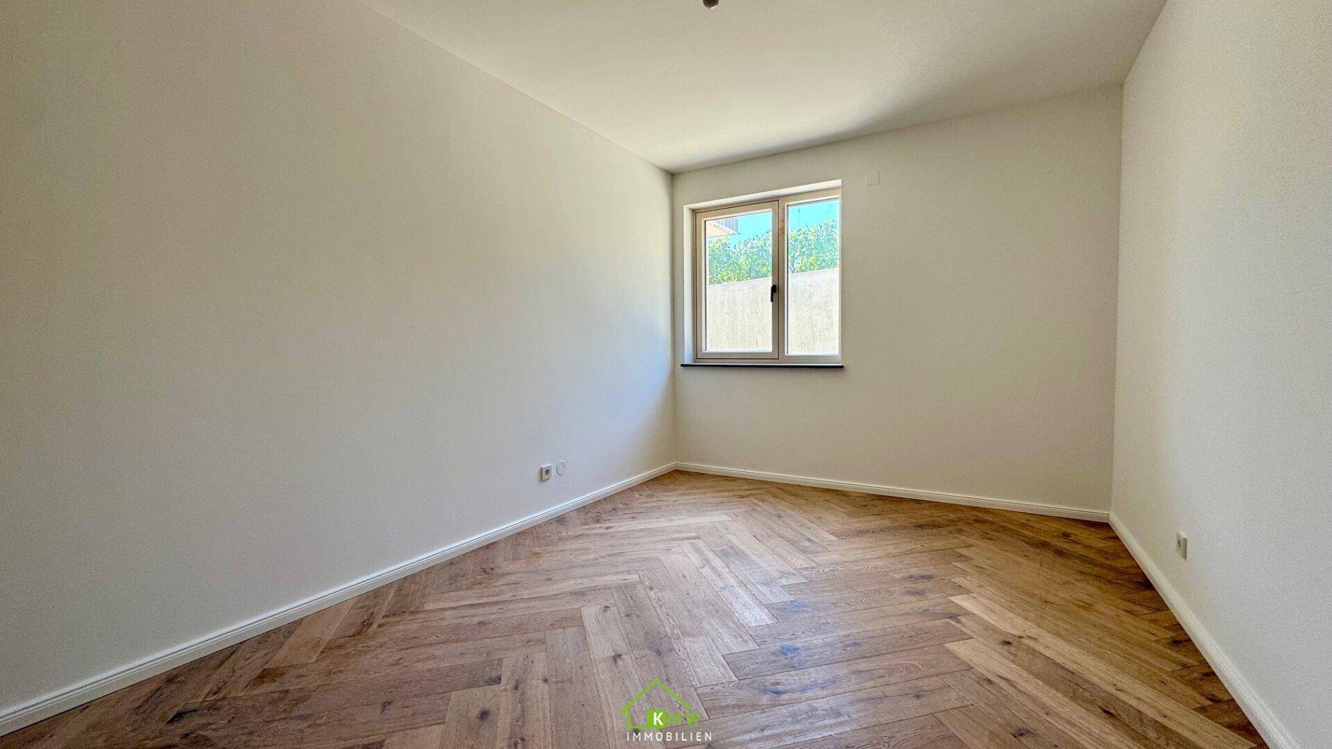 Helles Schlafzimmer mit elegantem Fischgrätparkett und einem einzelnen Fenster.