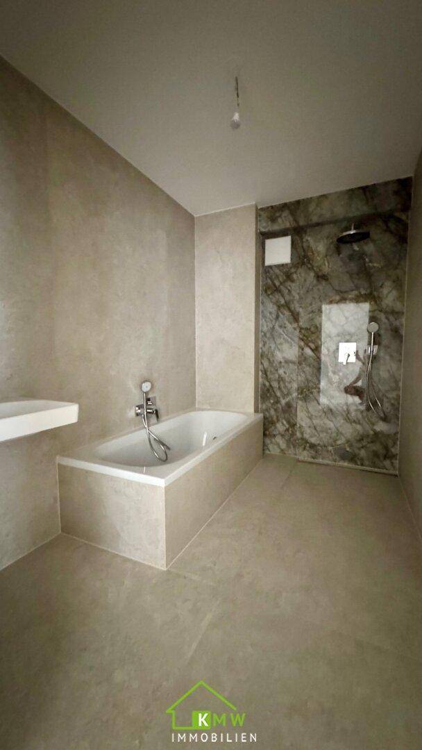 Modernes Badezimmer mit Badewanne und begehbarer Dusche, ausgestattet mit eleganten Marmorfliesen.
