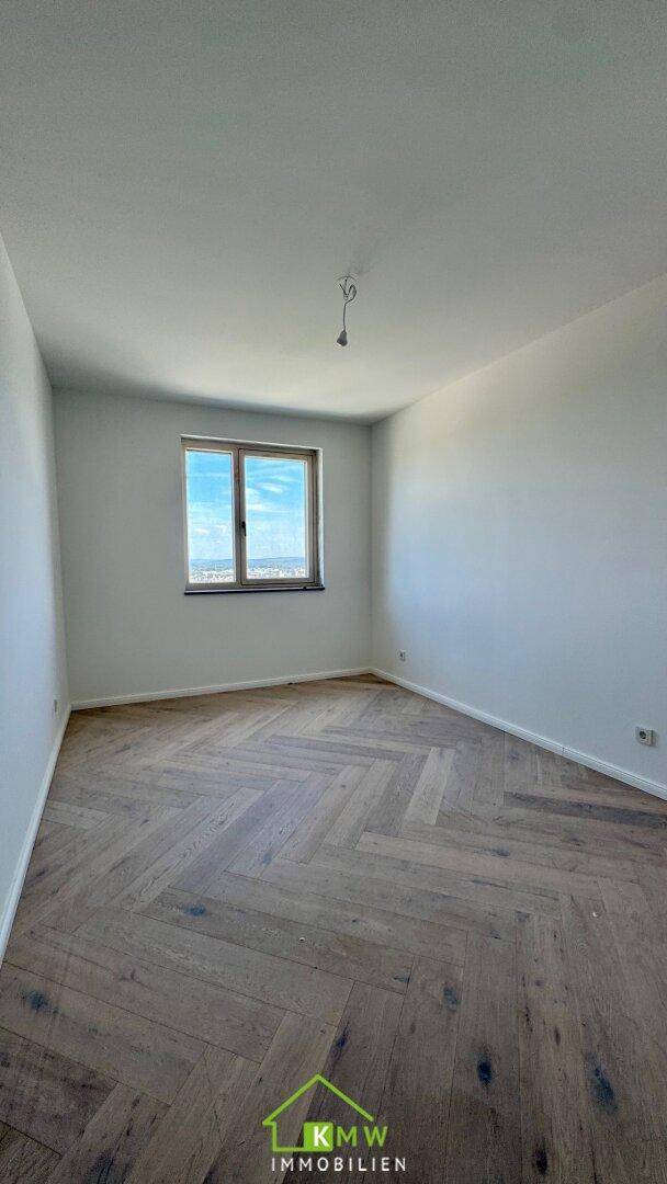Helles Zimmer mit Fischgrätparkettboden und weitem Ausblick.