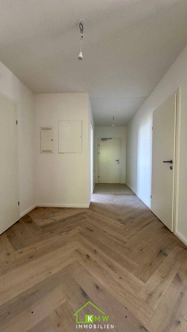 Geräumiger Flur mit elegantem Fischgrätparkett und weißen Türen.
