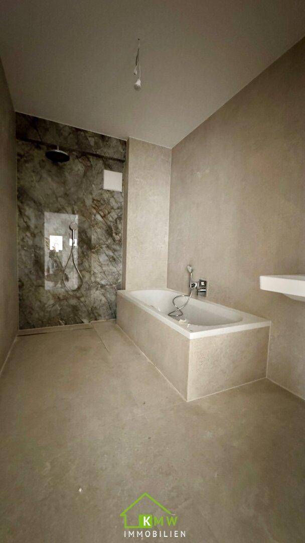 Modernes Badezimmer mit Badewanne und begehbarer Dusche, ausgestattet mit eleganten Marmorfliesen.