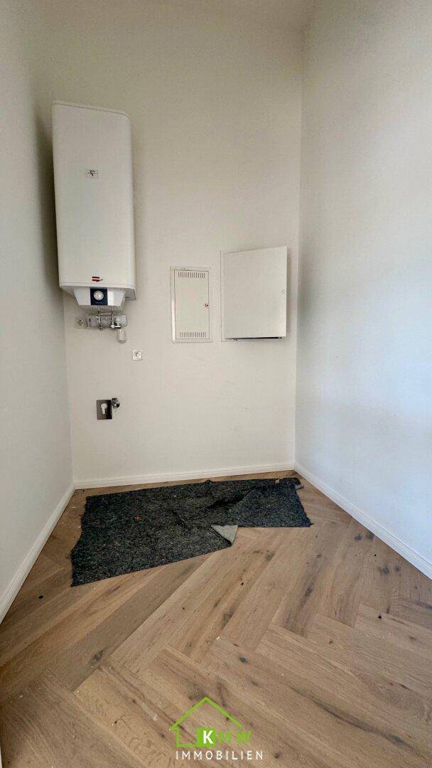 Praktischer Hauswirtschaftsraum mit Warmwasserboiler, Elektroverteilung und Fischgrätparkett.