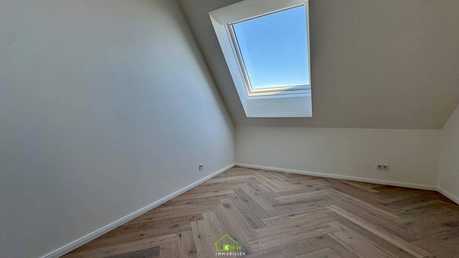 Helles Schlafzimmer mit Fischgrätparkett, Dachschräge und einem großen Dachfenster.