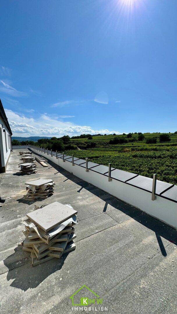 Dachfläche eines Neubaus mit Baumaterialien und Panoramablick auf die Weinberge.