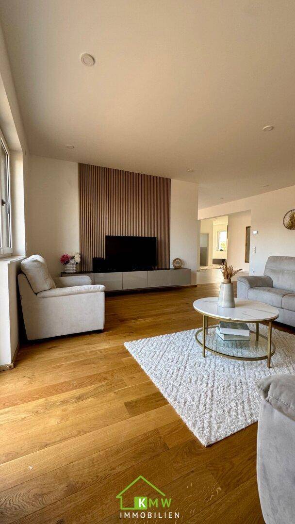 Gemütliches Wohnzimmer mit Holzboden, modernem Wandpaneel und hellem Teppich.