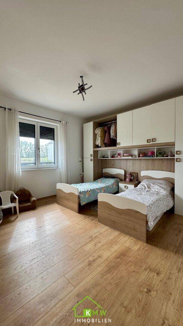 Kinderzimmer mit zwei Betten, Einbauschränken und Holzboden.