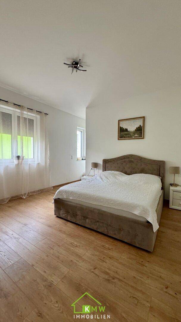 Helles Schlafzimmer mit Holzboden, bequemen Bett und Nachttischen.