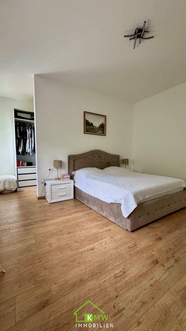 Schlafzimmer mit Holzboden und offenem Zugang zu einem begehbaren Kleiderschrank.