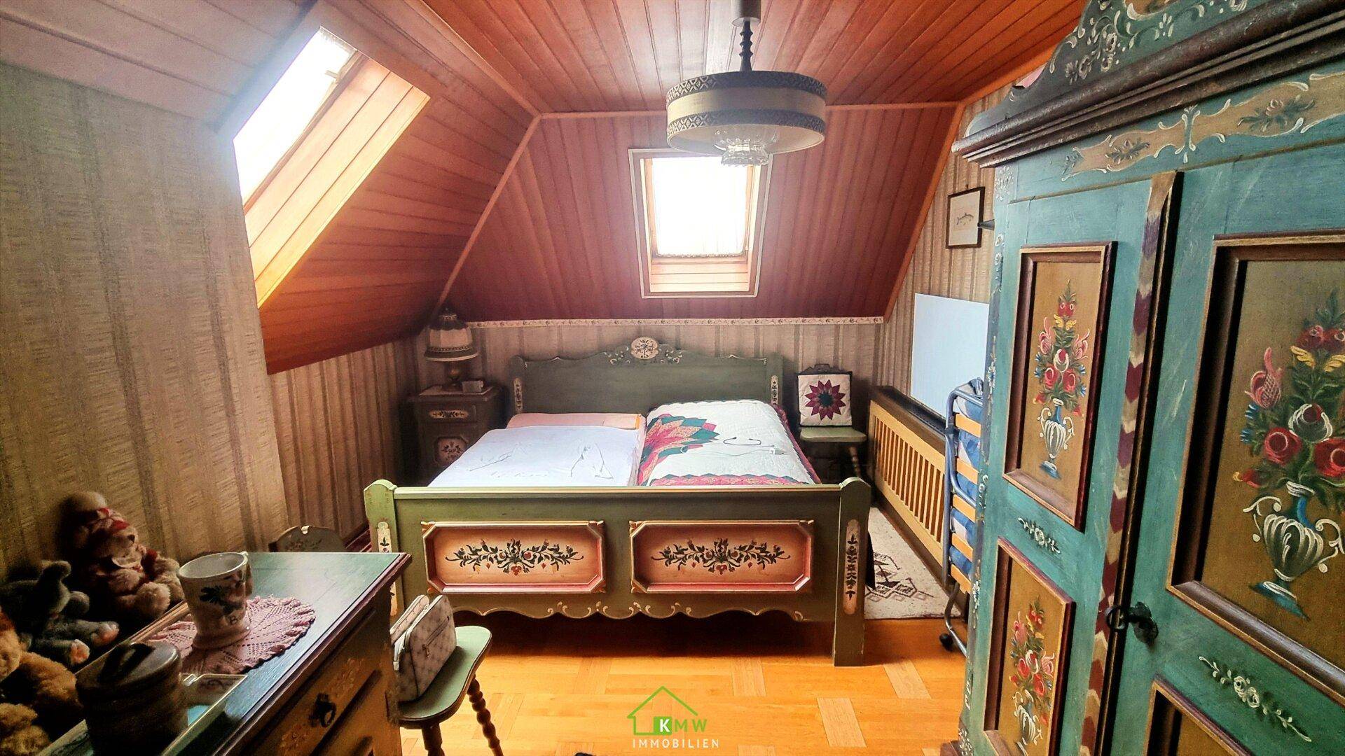 Rustikales Schlafzimmer im Dachgeschoss mit Holzvertäfelung, Dachfenstern und traditionellen Möbeln.