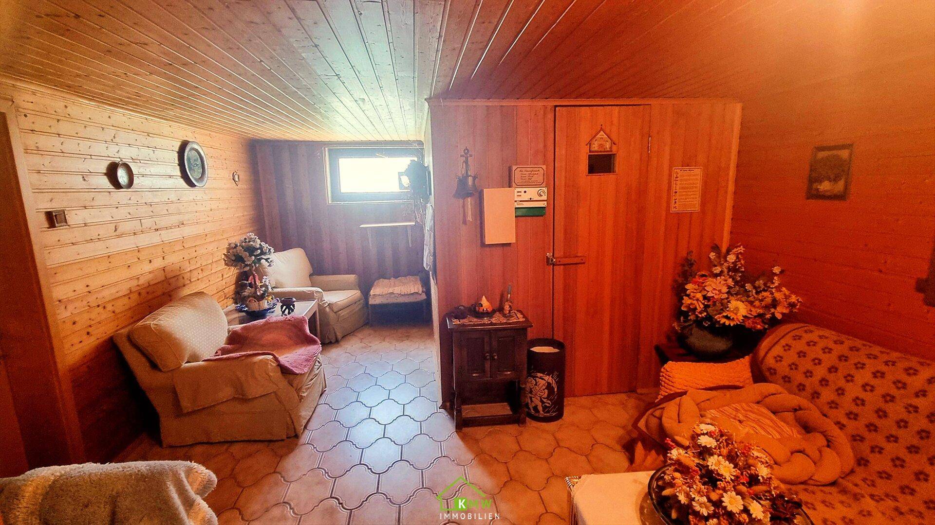 Gemütlicher Wellnessbereich mit Holzvertäfelung, Sitzgelegenheiten und Zugang zur Sauna.