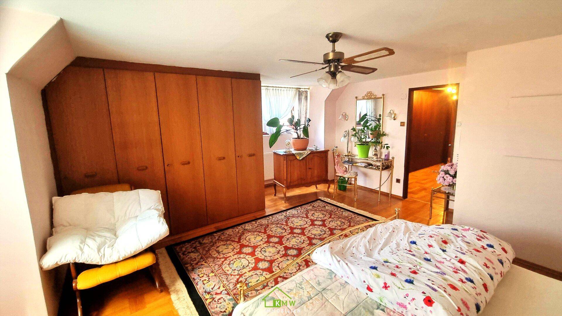 Geräumiges Schlafzimmer mit großem Kleiderschrank, Holzboden und Fenster mit viel Licht.