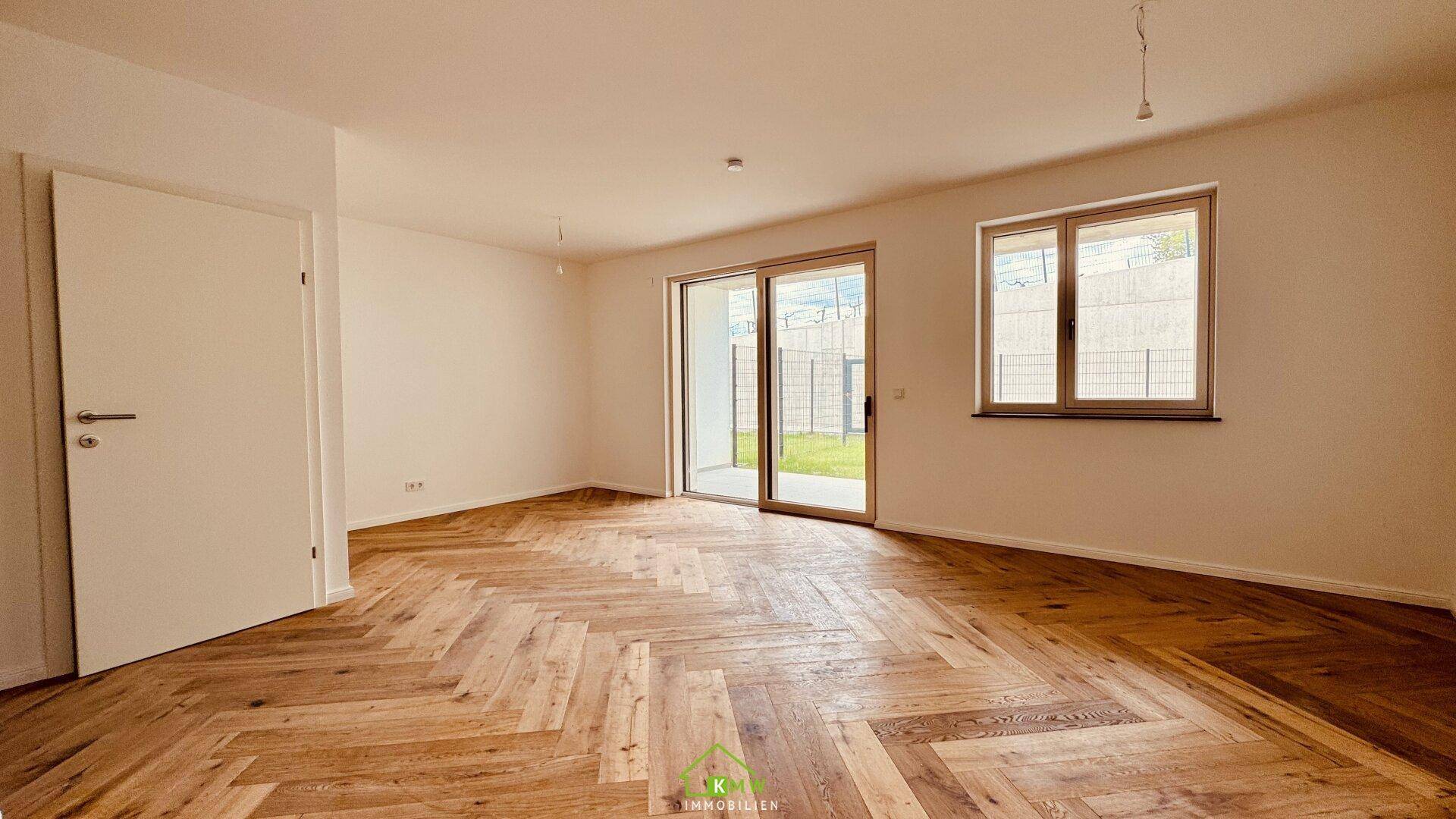 Heller Wohnraum mit elegantem Fischgrätparkett und großem Schiebetürzugang zur Terrasse und zum Garten.