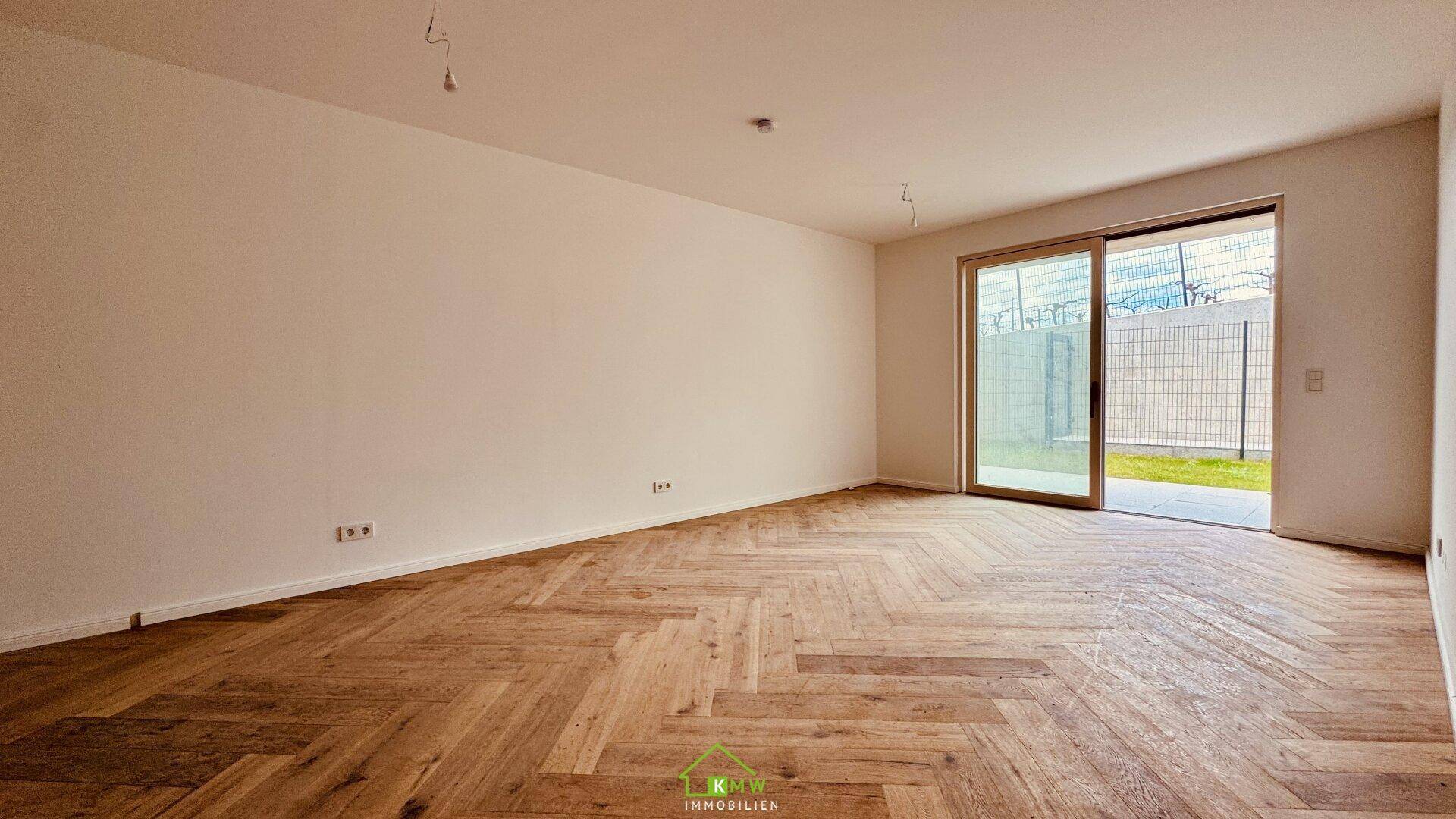 Lichtdurchfluteter Wohnbereich mit hochwertigem Fischgrätparkett und direktem Gartenzugang.