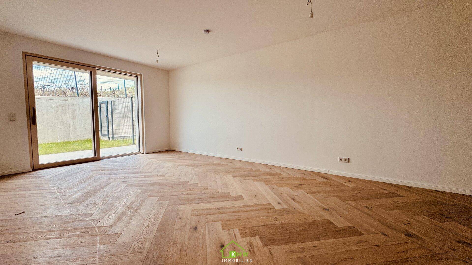 Lichtdurchfluteter Wohnraum mit neuem Fischgrätparkett und direktem Zugang zum Außenbereich.