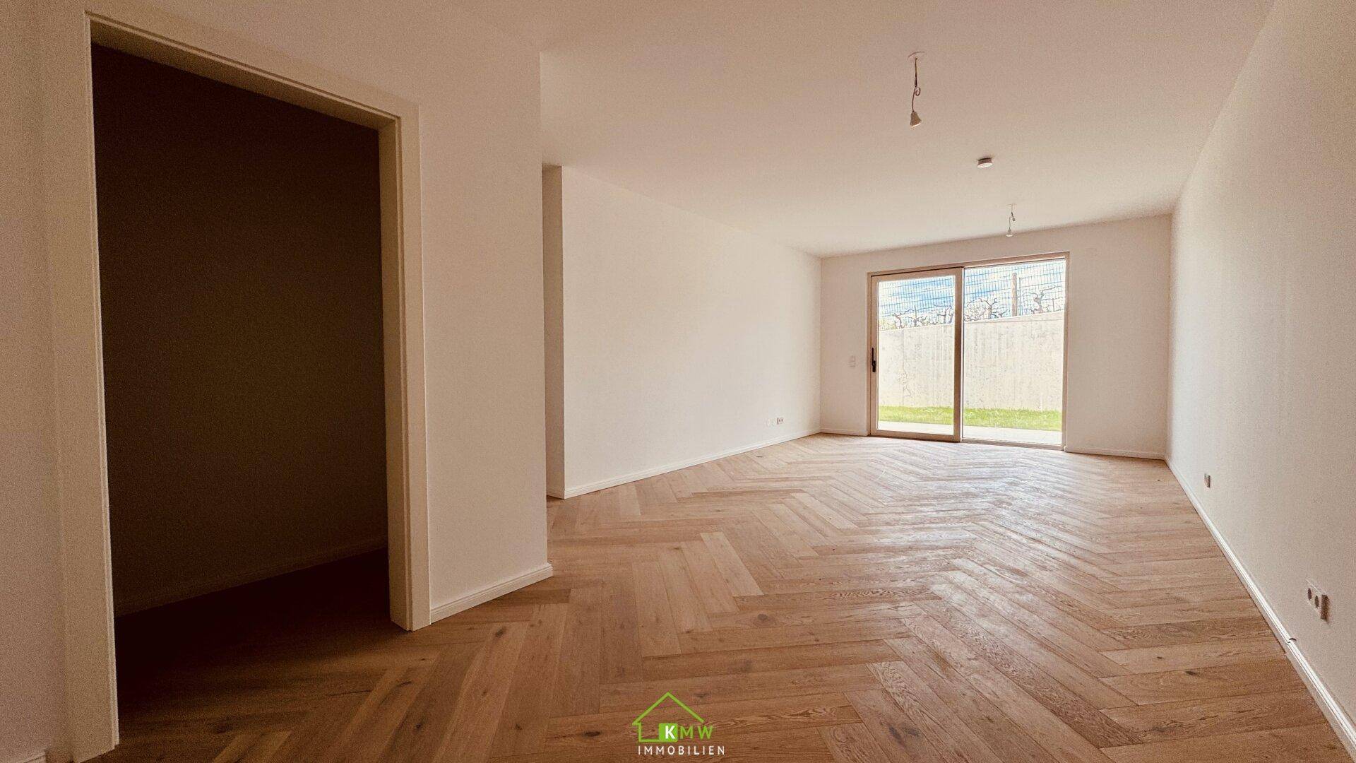 Heller Wohnraum mit elegantem Fischgrätparkett und Zugang zur Terrasse oder Garten.