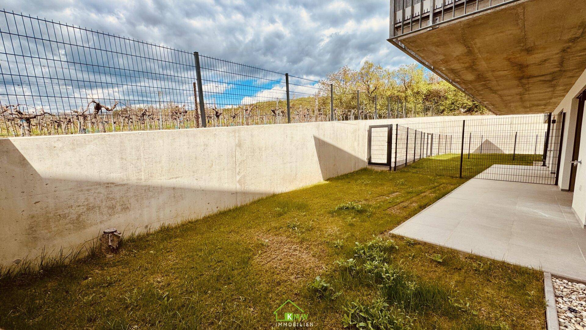 Gepflegter Gartenbereich mit Betonmauer und Blick auf umliegende Weinberge.