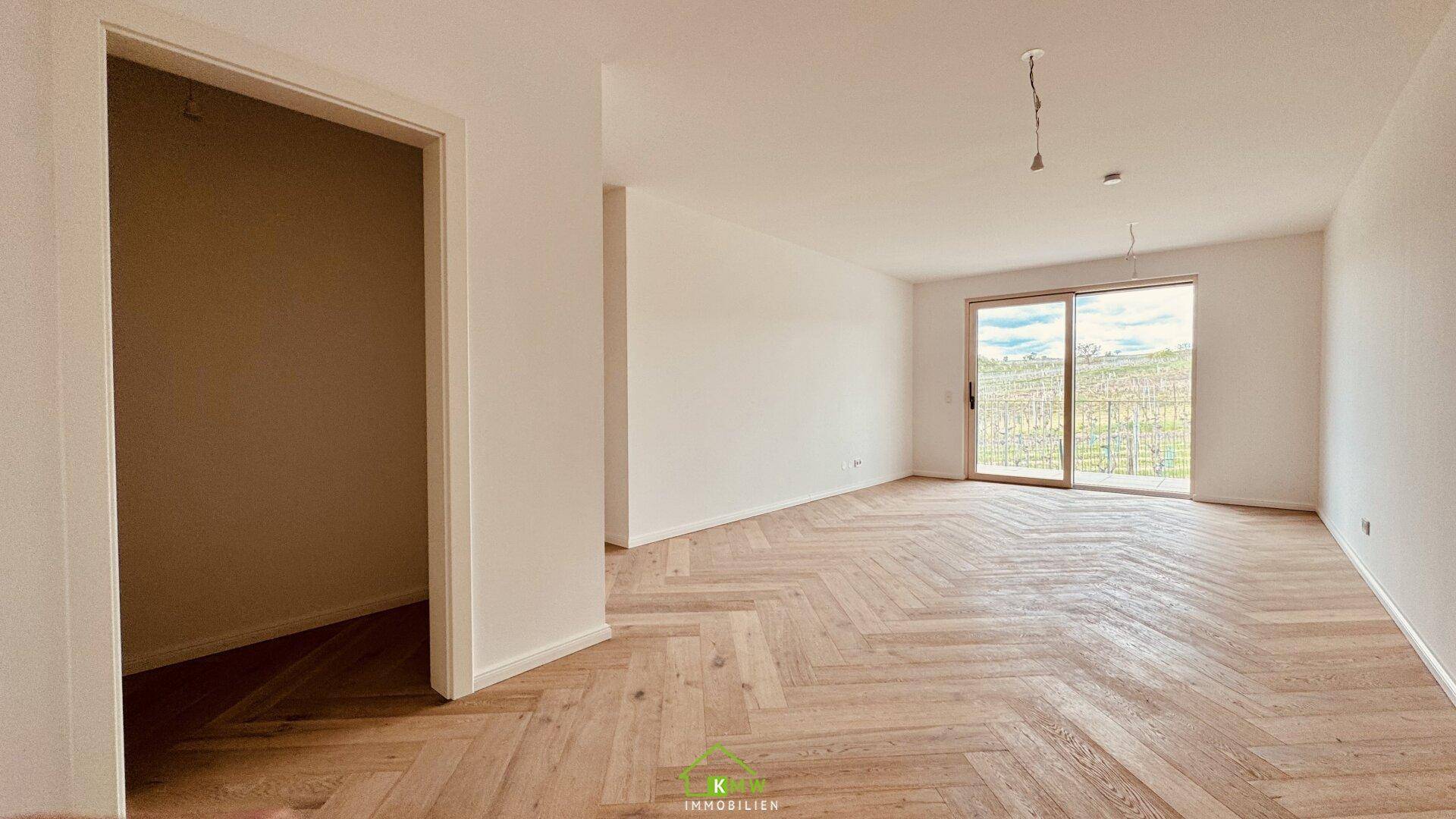 Heller Wohnraum mit elegantem Fischgrätparkett und großem Schiebefenster mit Blick auf die Weinberge.
