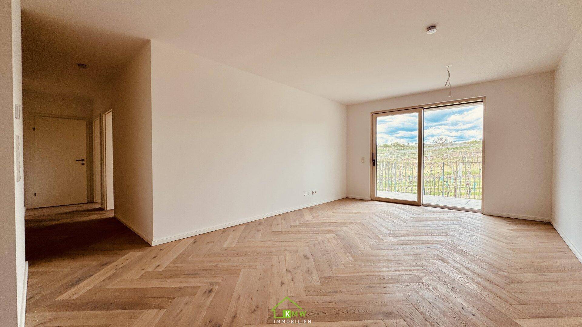 Lichtdurchfluteter Wohnbereich mit hochwertigem Fischgrätparkett und Zugang zu einem weiteren Zimmer.