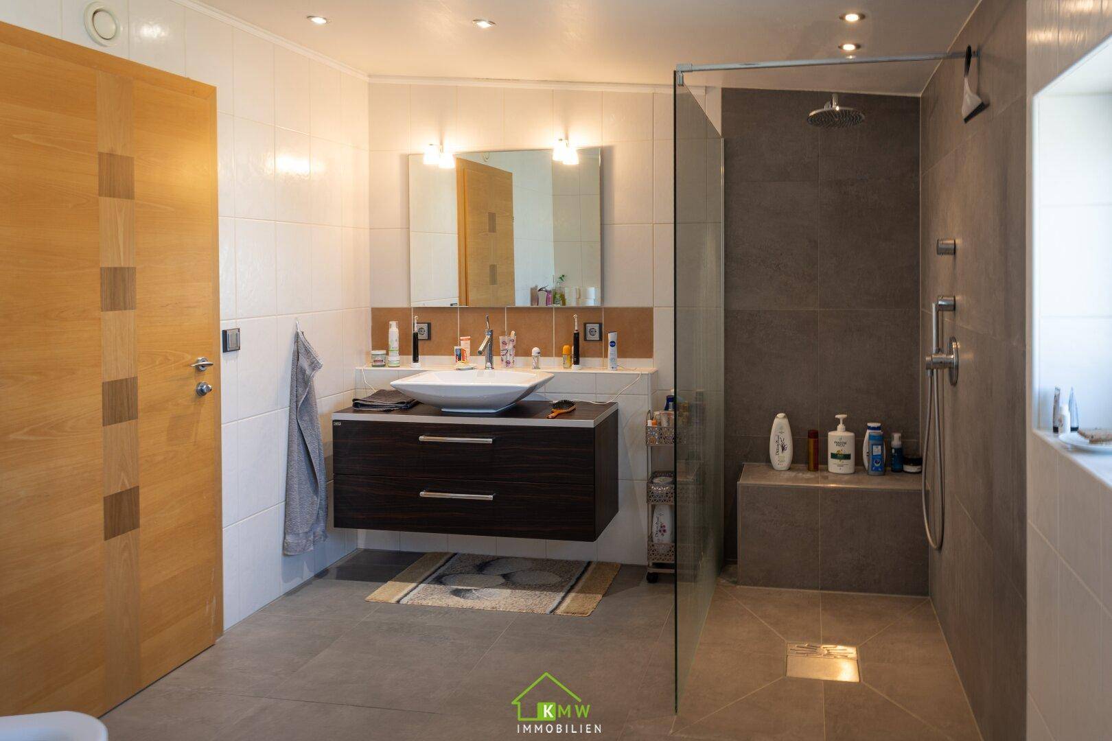 Modernes Badezimmer mit großer begehbarer Dusche, stilvollem Waschtisch und Einbauspiegel.