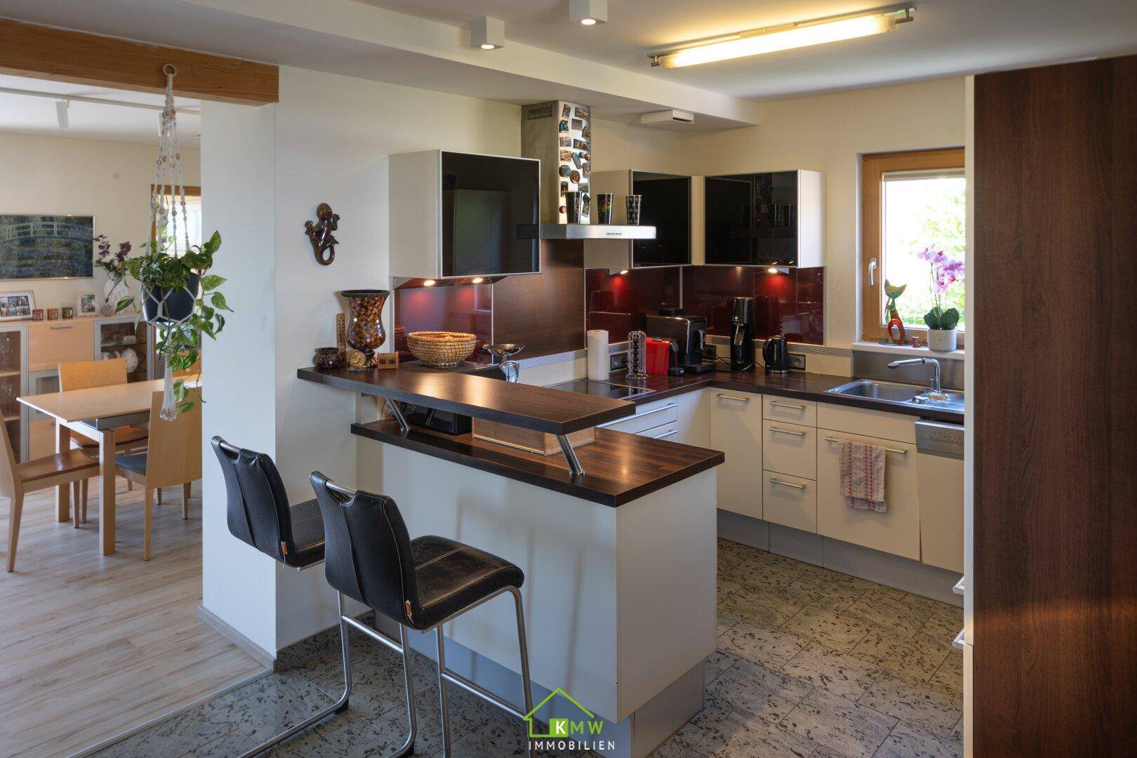Offene Küche mit Frühstücksbar, modernen Einbauschränken und Blick ins Esszimmer.