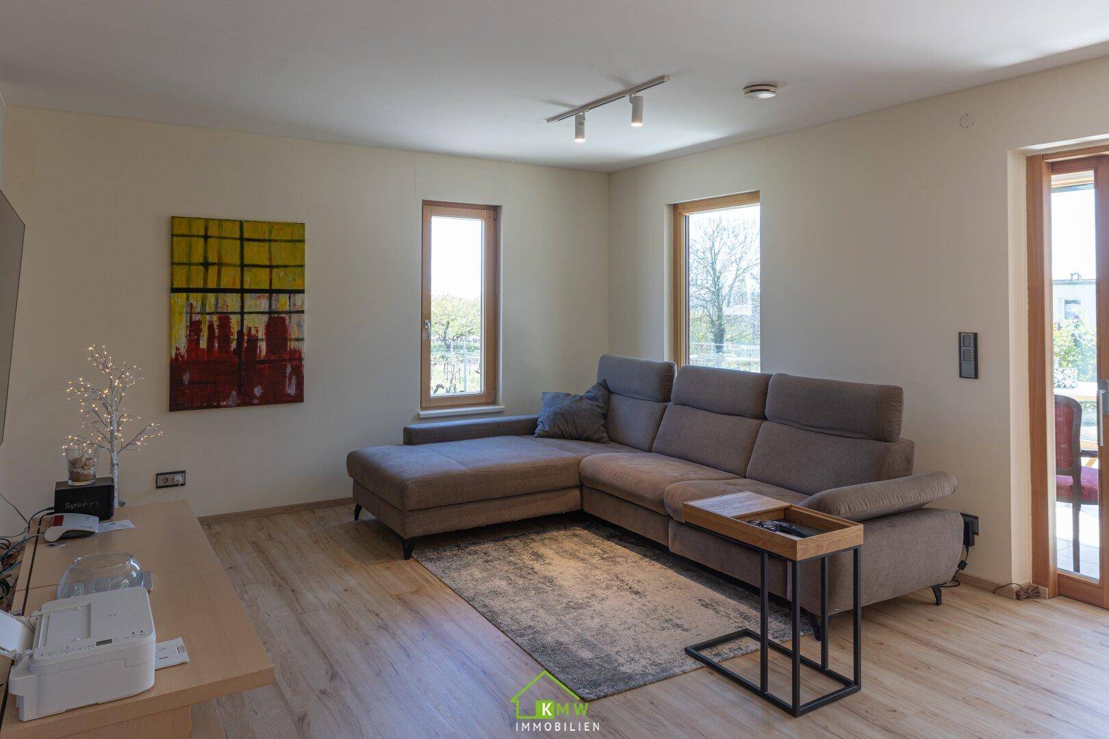Geräumiges Wohnzimmer mit großer Eckcouch, modernem Teppich und hellem Laminatboden.