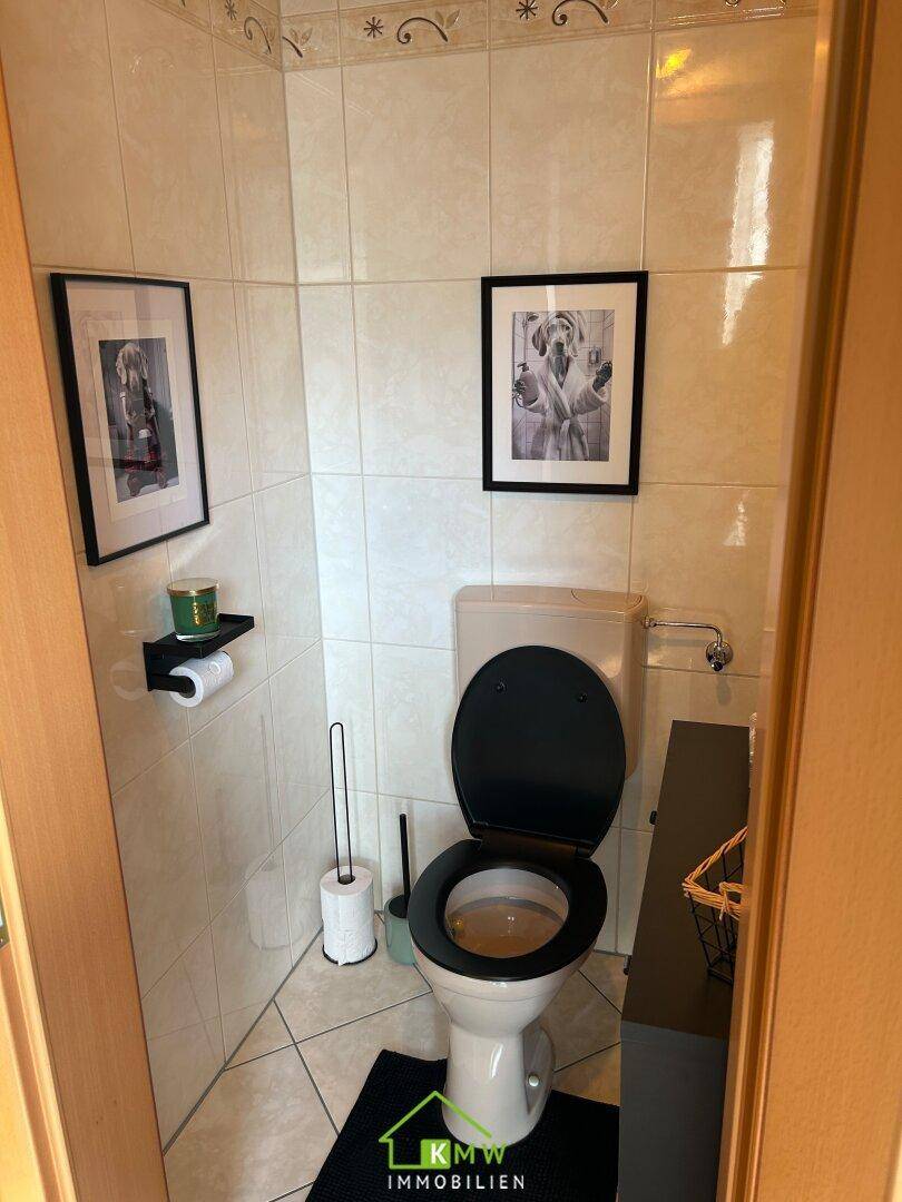Kleines Gäste-WC mit weißen Fliesen, Toilette und einfacher Dekoration.