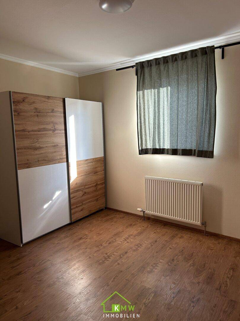 Schlafzimmer mit großem Kleiderschrank, Fenster und Holzboden, bietet viel Stauraum.