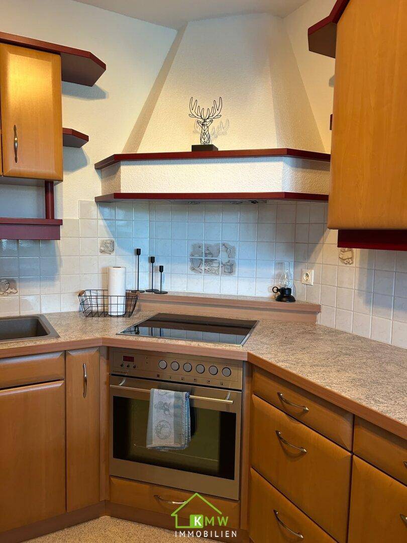 Gemütliche Küche mit Holzelementen, Induktionskochfeld und Backofen in einer Ecke.
