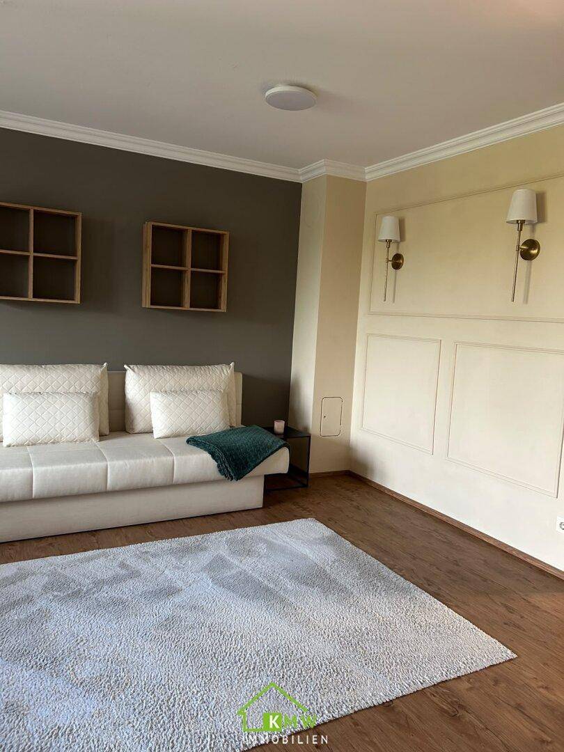 Gemütliches Wohnzimmer mit weißem Sofa, Wandleuchten und Holzboden, einladend gestaltet.