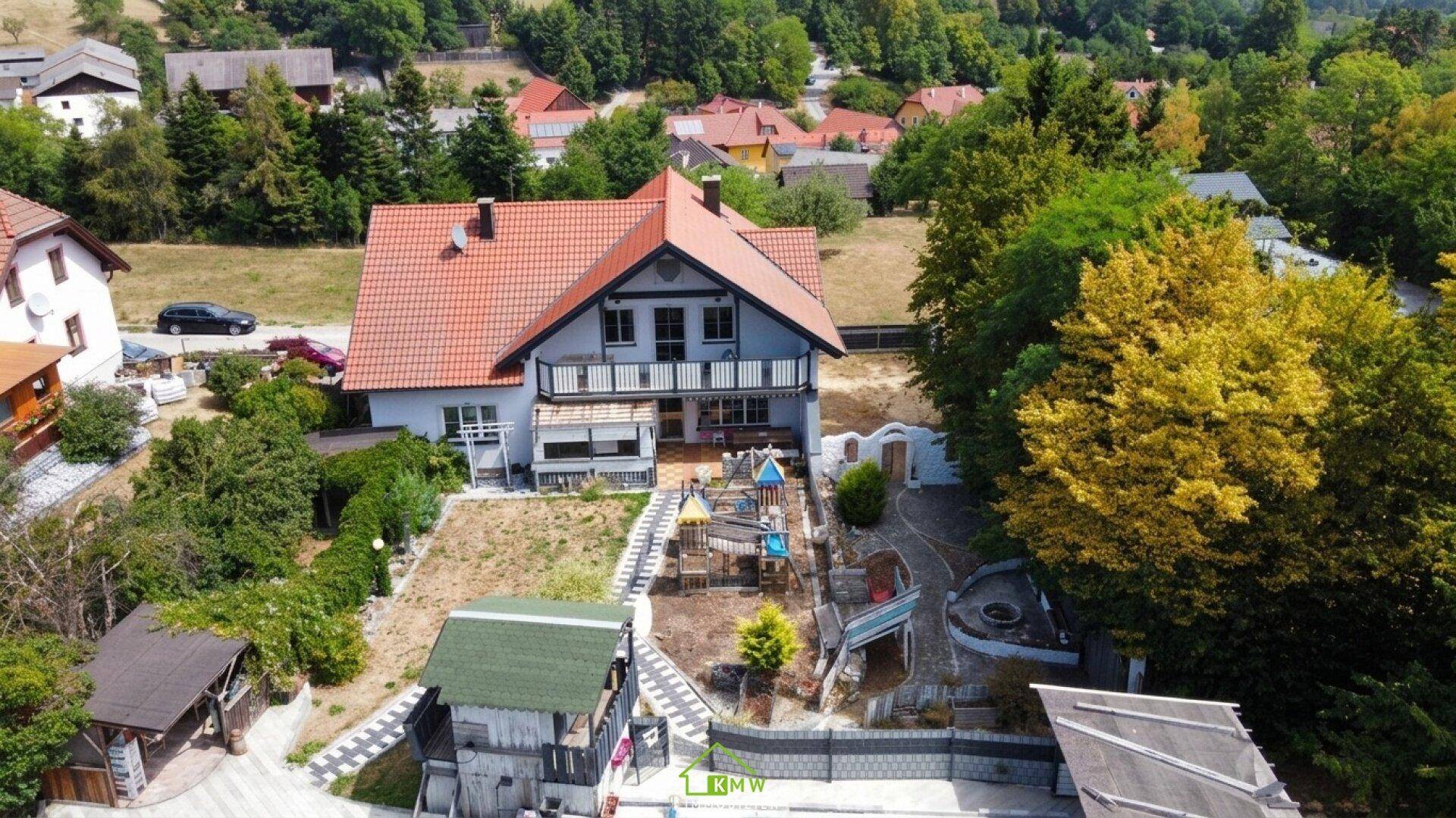 Luftaufnahme eines Hauses mit großem Garten, Kinderspielplatz und angrenzenden Feldern.