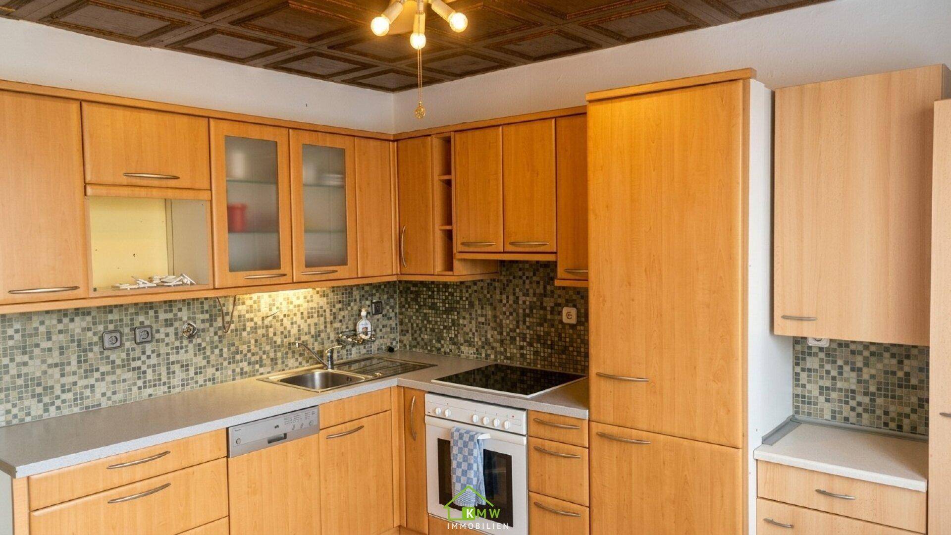 Funktionale Holzküche mit Mosaikfliesen, Einbaugeräten und einer dekorativen Kassettendecke.