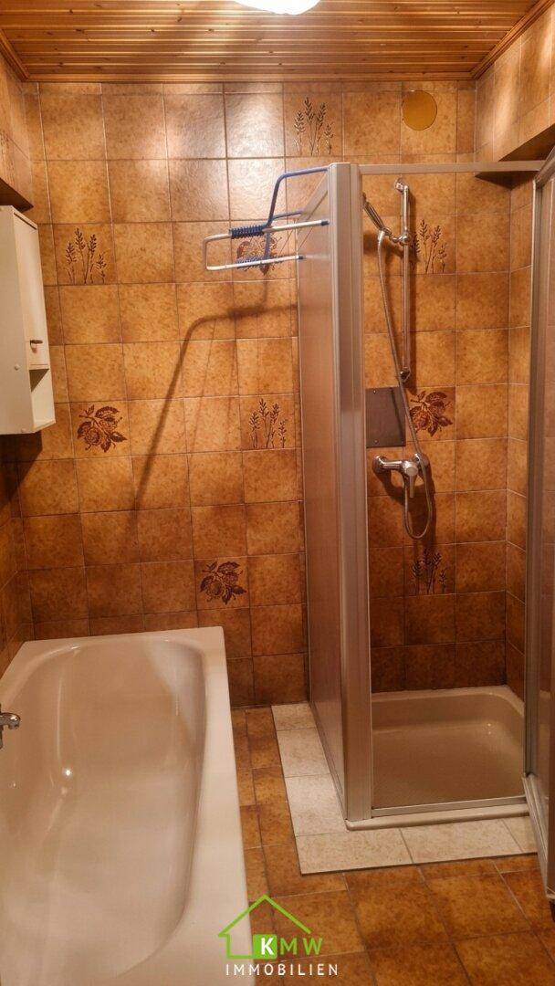 Badezimmer mit braunen Fliesen, einer Badewanne und einer Duschkabine, ausgestattet im traditionellen Stil.