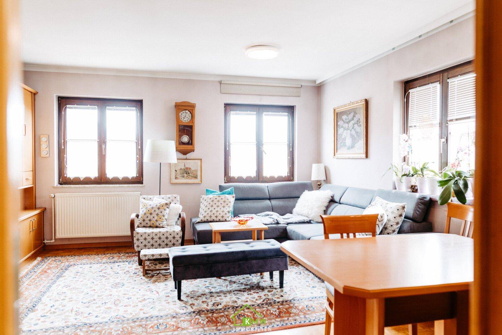 Heller Wohn- und Essbereich mit bequemer Couch, Teppich und traditionellen Holzmöbeln.