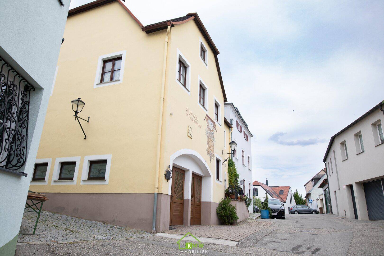 Seitenansicht des historischen Gebäudes mit heller Fassade und traditionellen Fenstern in einer Gasse.