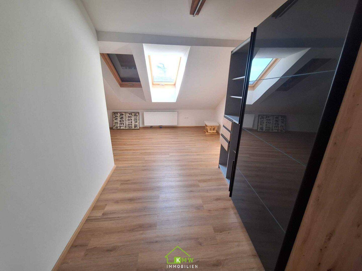 Heller Flurbereich im Dachgeschoss mit Laminatboden und Dachfenstern, die Tageslicht hereinlassen.