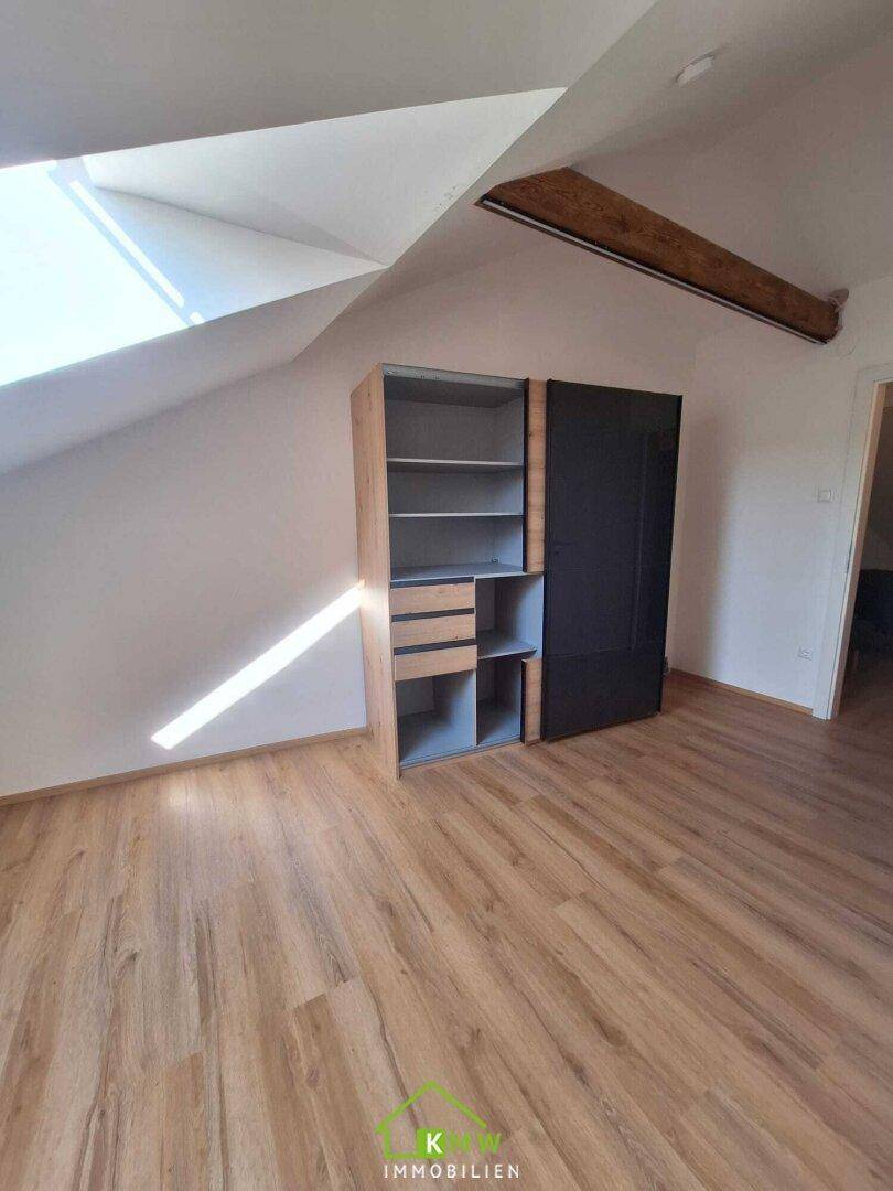 Schlafzimmer oder Ankleidebereich im Dachgeschoss mit Einbauschrank, Laminatboden und Dachfenster.