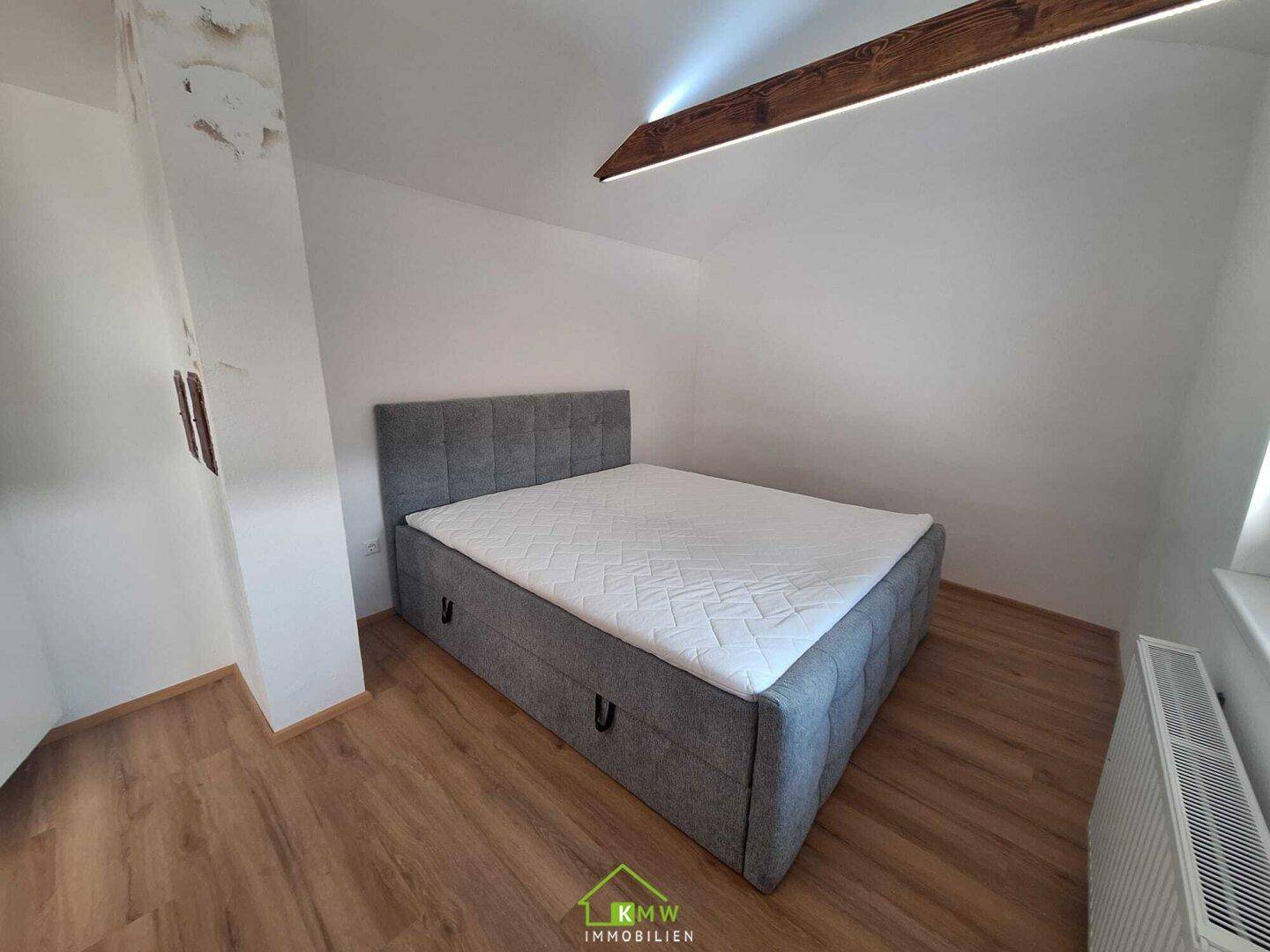 Gemütliches Schlafzimmer im Dachgeschoss mit Doppelbett, Laminatboden und Heizkörper.