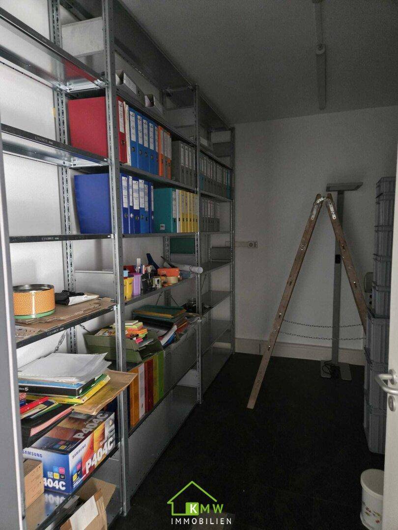 Abstellraum mit Metallregalen, gefüllt mit Aktenordnern und Büromaterial, gut organisiert.