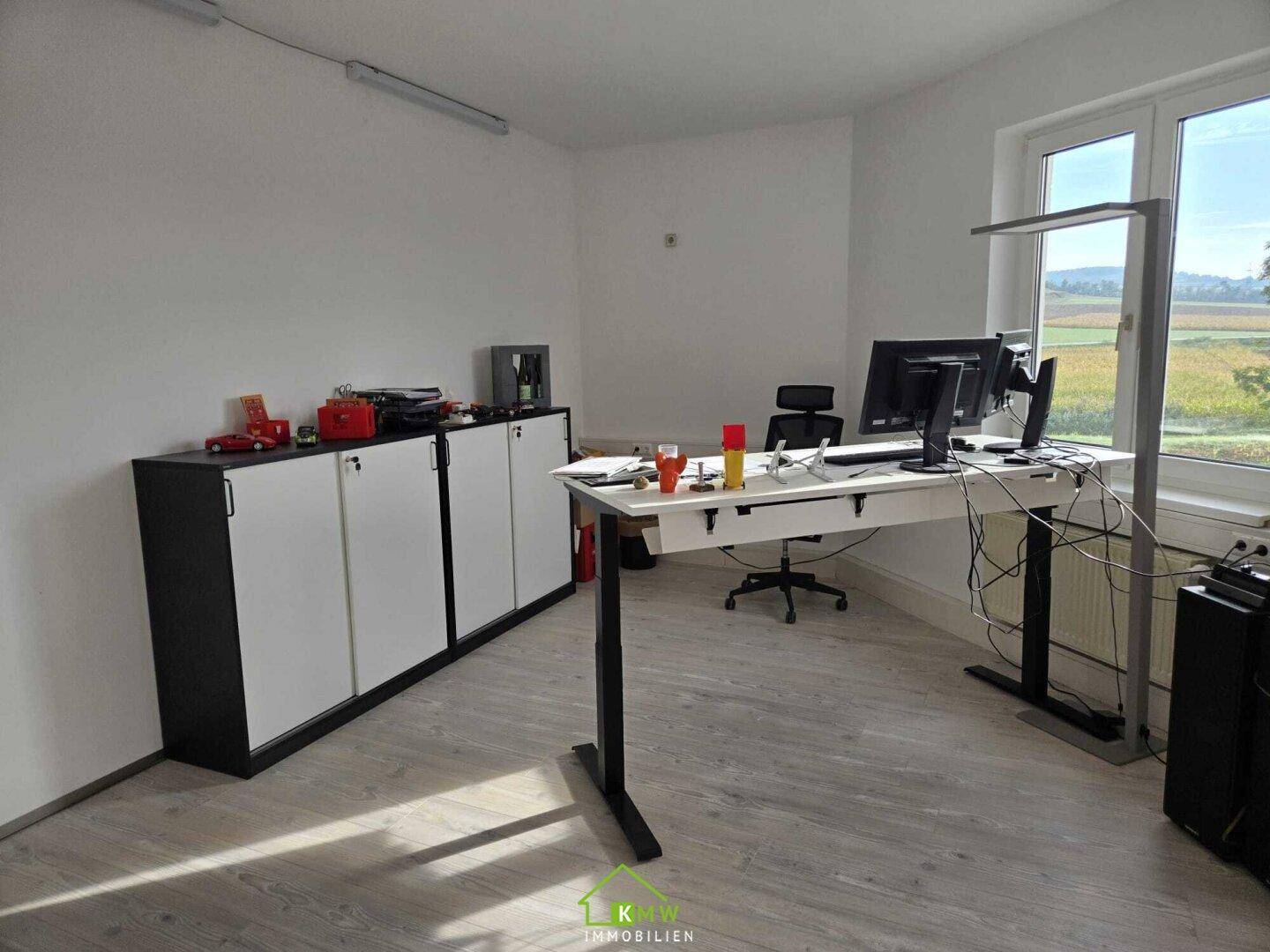 Büro mit Schreibtisch, Aktenschränken und weitem Blick auf die umliegende Landschaft durch das Fenster.
