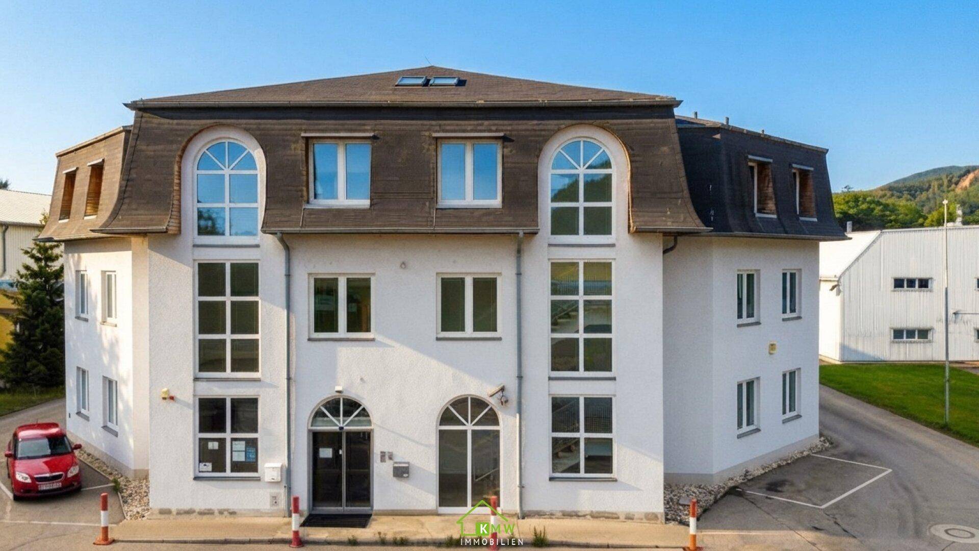 Vorderansicht des modernen Geschäftsgebäudes mit markanten Rundbogenfenstern und weißer Fassade.
