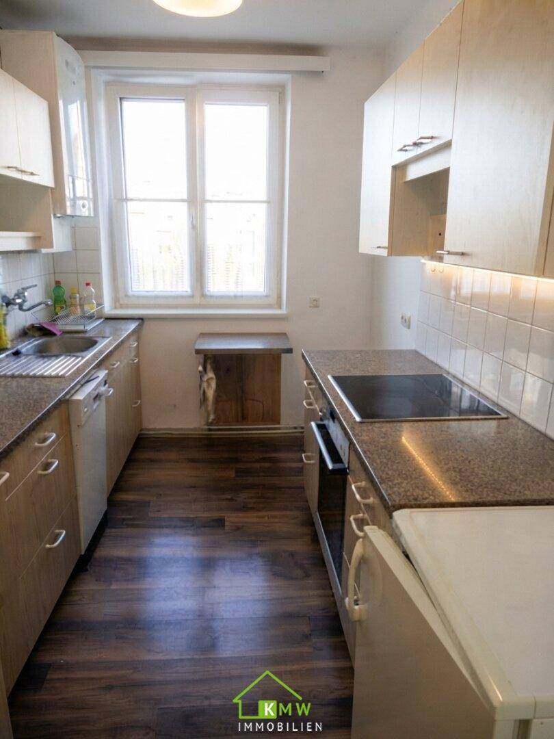 Funktionale Küche mit Granitarbeitsplatten, Einbaugeräten und einem Fenster für Tageslicht.