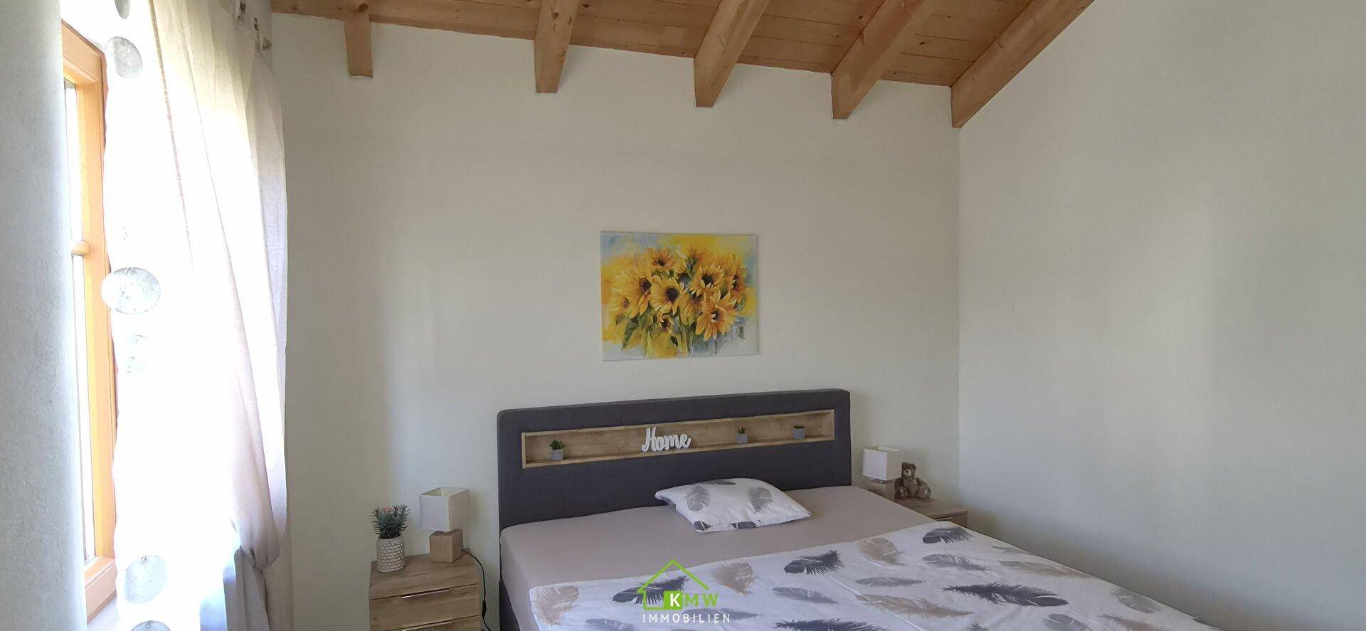 Helles Schlafzimmer mit Doppelbett, schlichten Möbeln und Fenster.