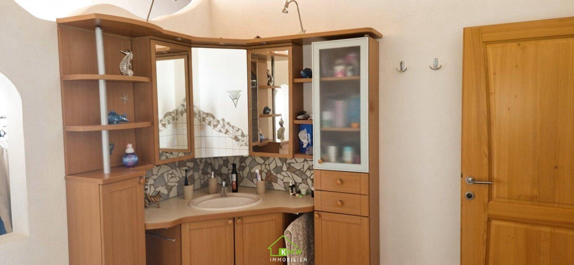 Badezimmer mit Holzmöbeln, Einzelwaschbecken und Spiegelschrank.
