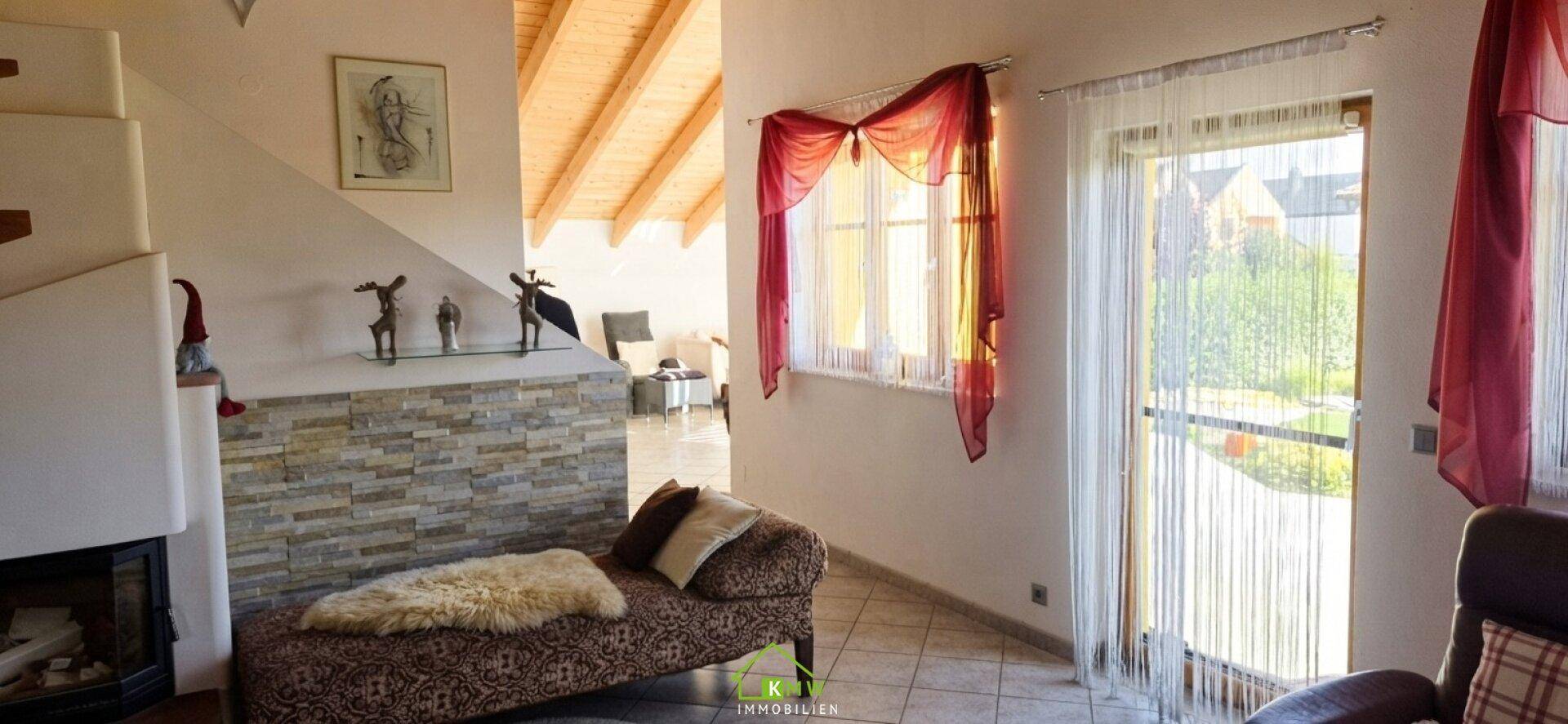 Heller Wohnbereich mit Kamin, Fliesenboden und Zugang zum Außenbereich.