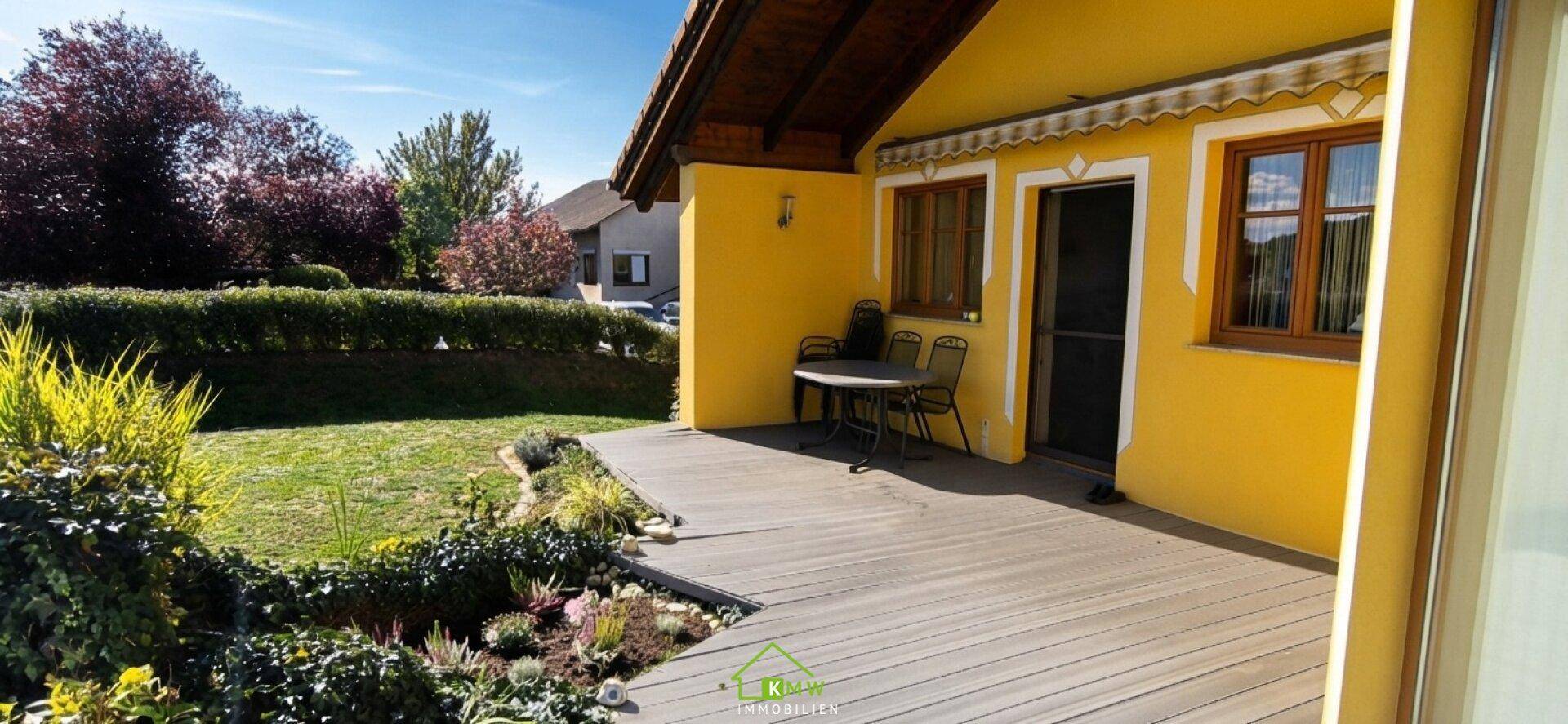 Gemütliche Holzterrasse mit Sitzgelegenheiten und Blick in den Garten.
