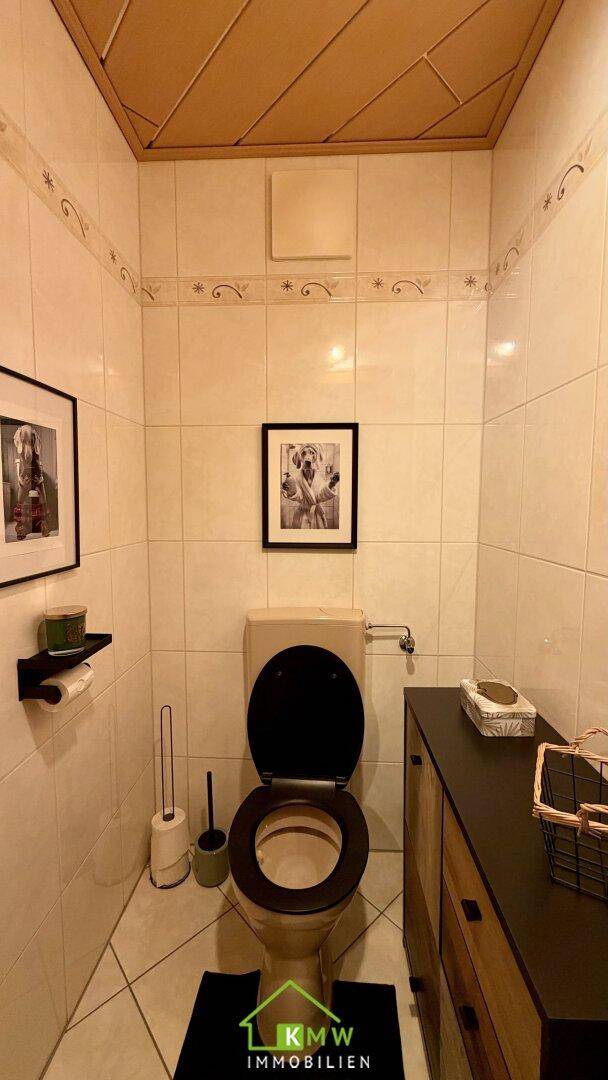 Separates WC mit Fliesenboden und kleinem Waschbecken.
